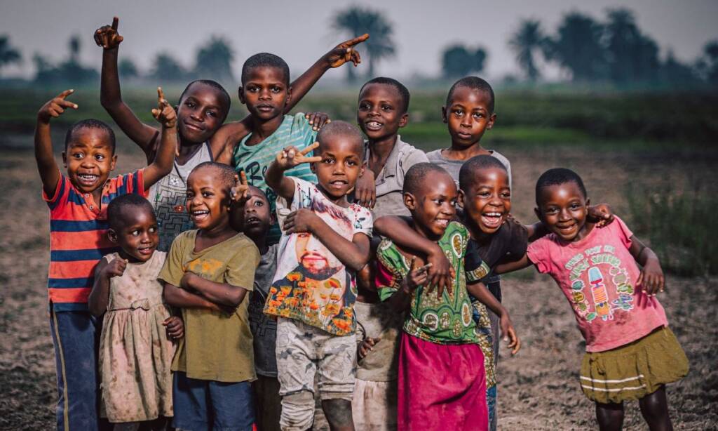 A group of children laughing and waving together outdoors