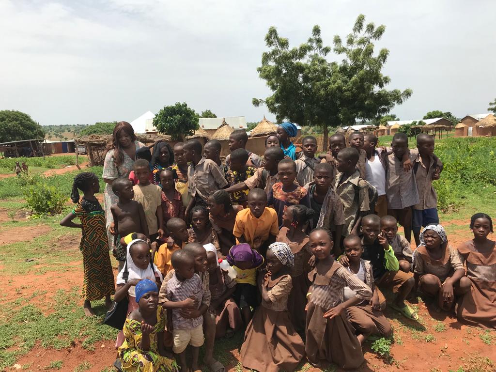 A large group of children and adults gathered under a tree