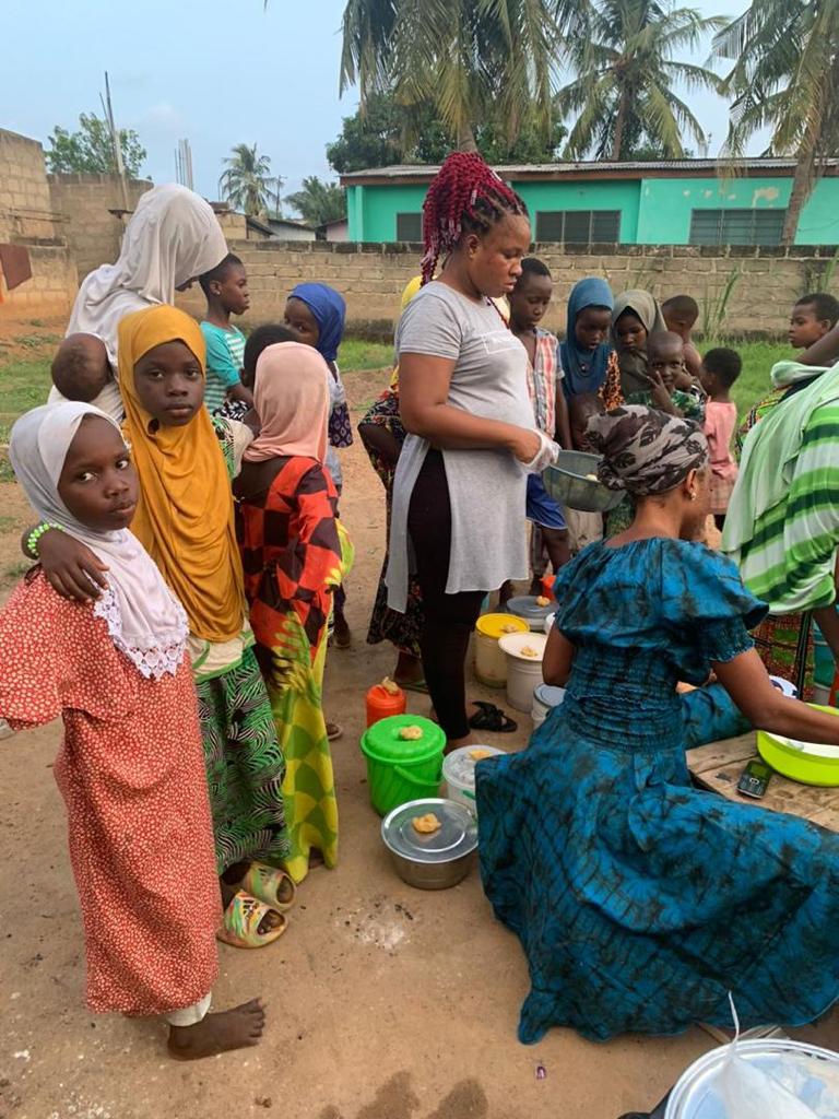 Women and children sharing food from large bowls outdoors