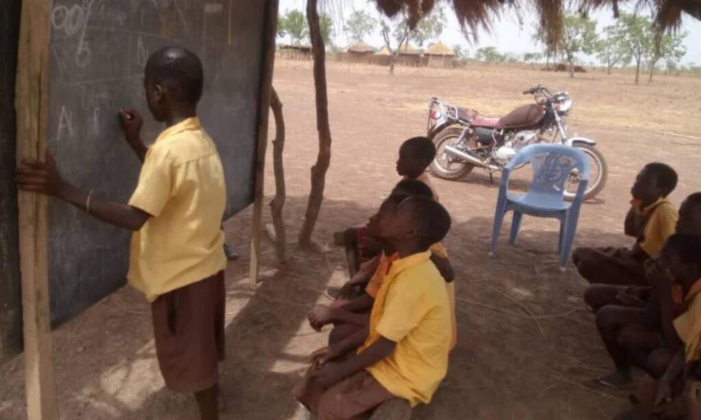 A boy writing on a blackboard during an outdoor lesson in northern Ghana