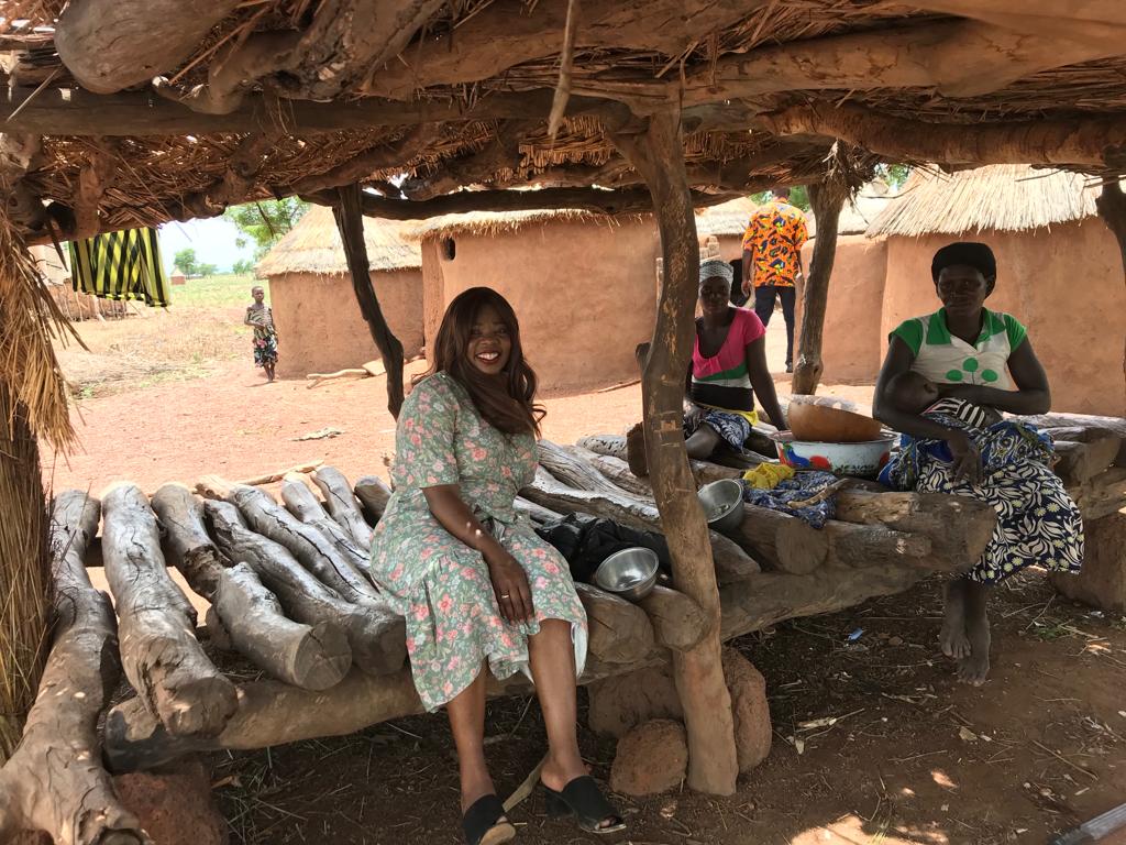 Women sitting in the shade of a thatched shelter in a village