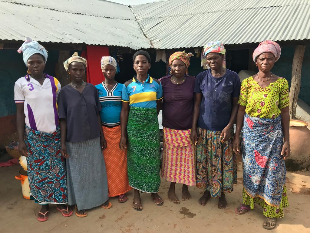 A group of women standing in front of a village building
