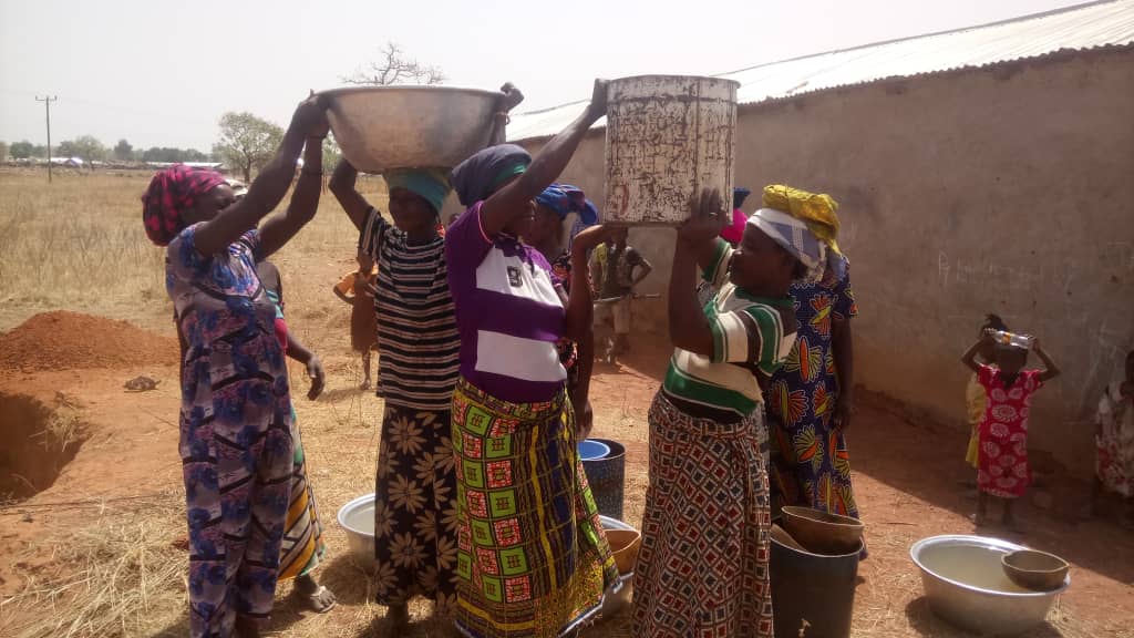 Women carrying metal bowls on their heads in a village in northern Ghana