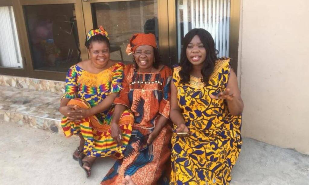 Three women in bright patterned dresses seated together