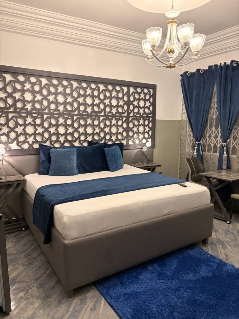 A guest room with blue cushions, a navy runner, a blue rug and a lattice headboard panel