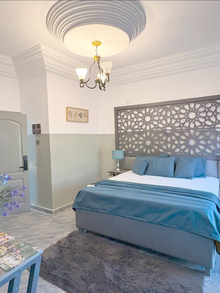 A guest room with teal bedding and a lattice headboard panel