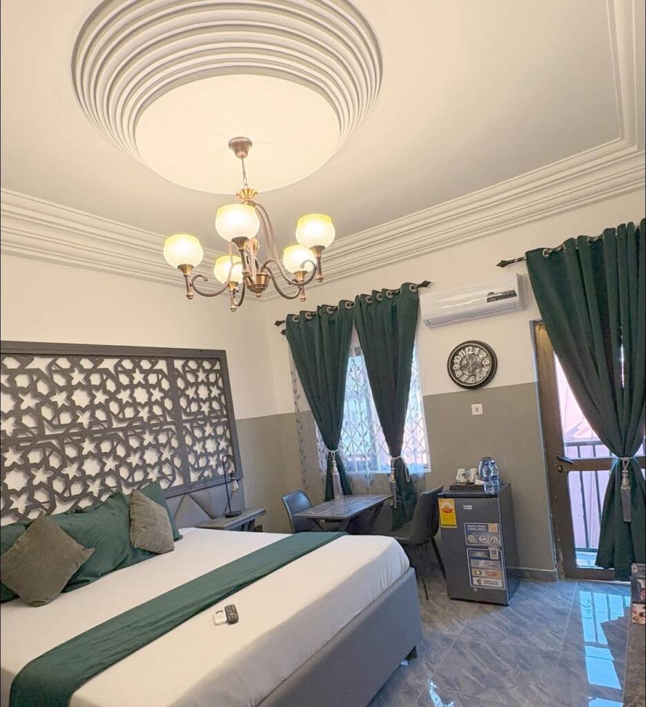 A guest room with a green bed runner, green curtains and a chandelier