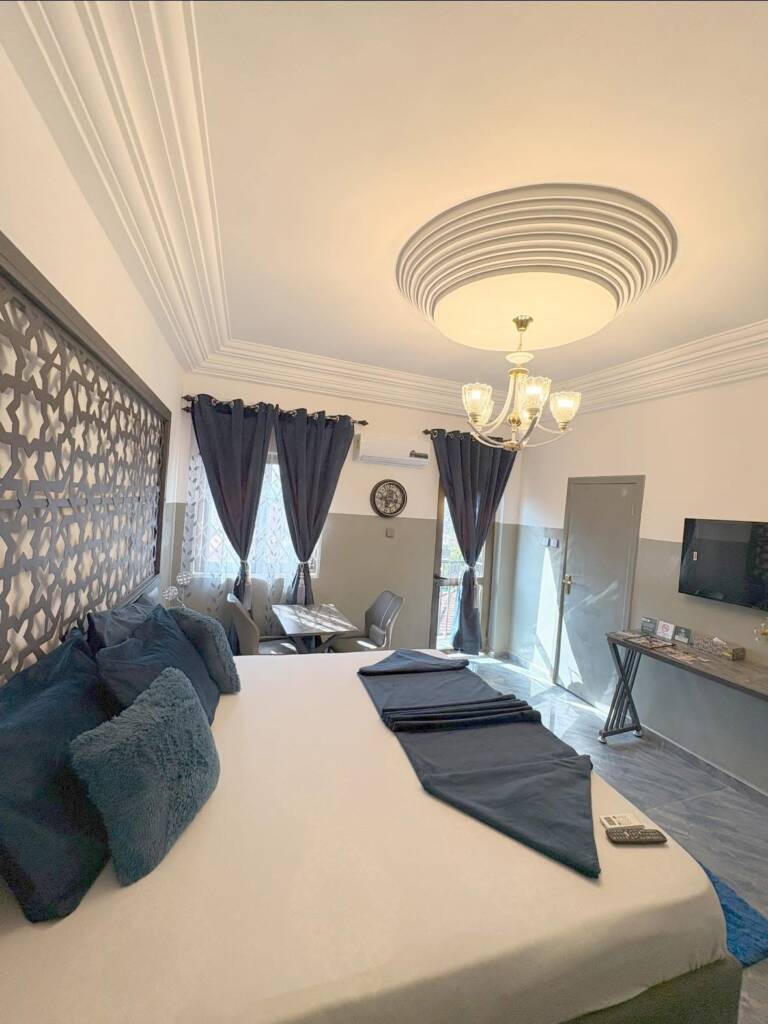 A guest room with blue cushions, a navy runner and a lattice headboard panel
