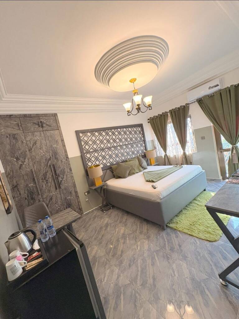 A guest room with a green rug, a lattice headboard panel and a tea tray on the desk