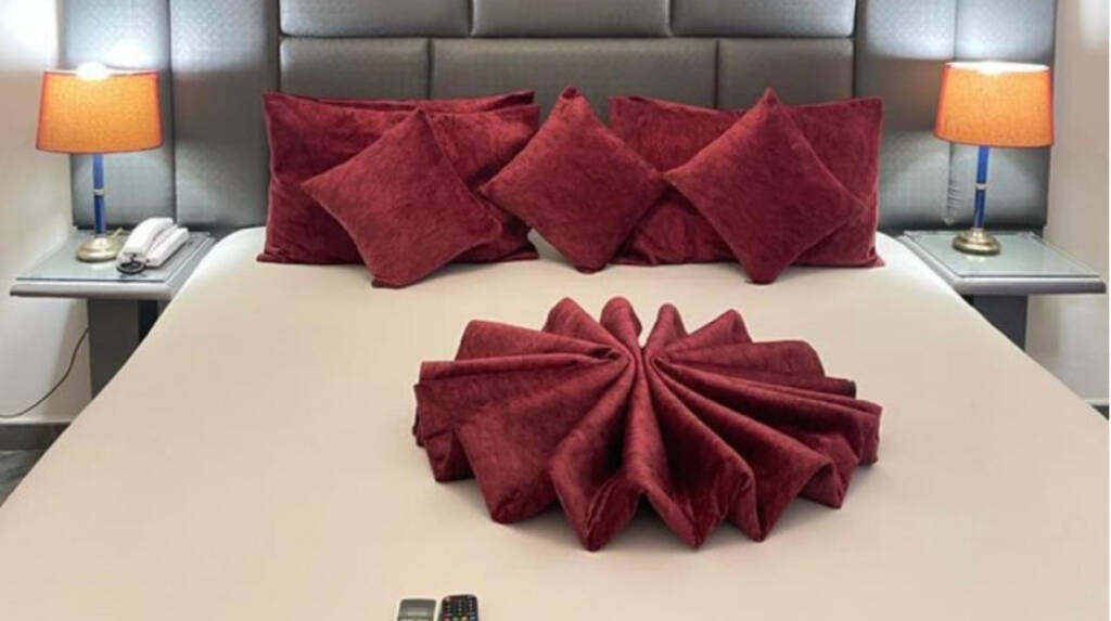 A king room at the Perriman Hotel, with red cushions and a towel folded into a fan