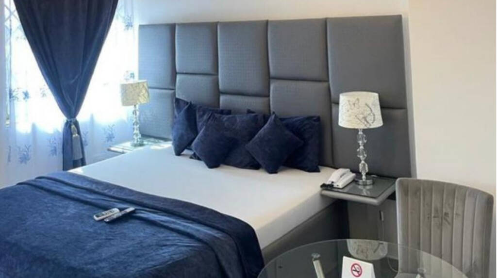 A queen room at the Perriman Hotel, with navy bedding and a padded grey headboard