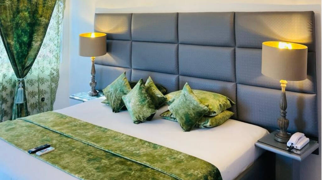 A super deluxe king room at the Perriman Hotel, with green cushions and bedside lamps