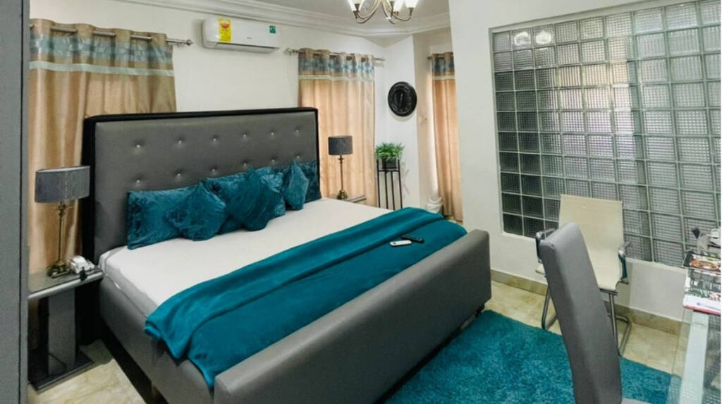 A super king room at the Perriman Hotel, with teal bedding and a glass-block window