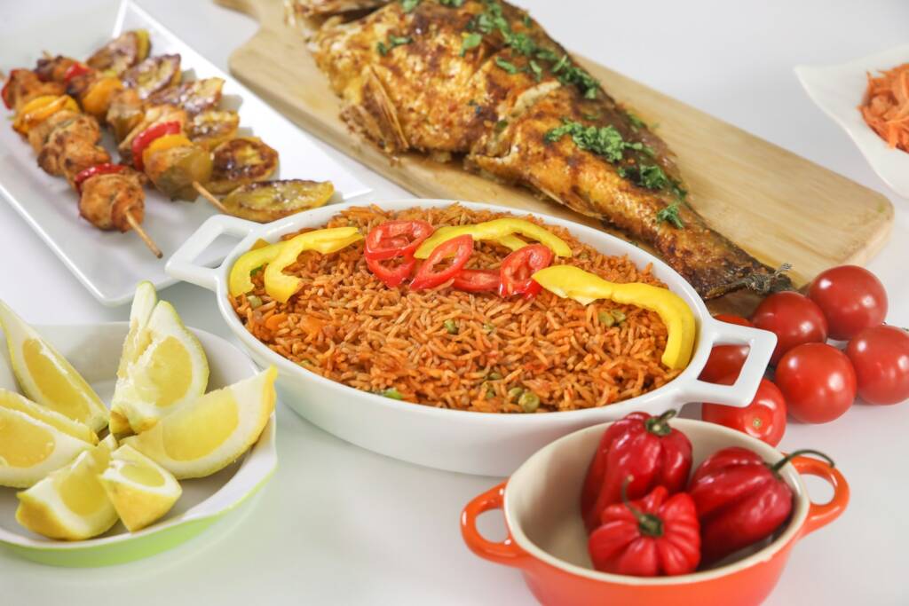 Jollof rice served with grilled fish, peppers and tomatoes